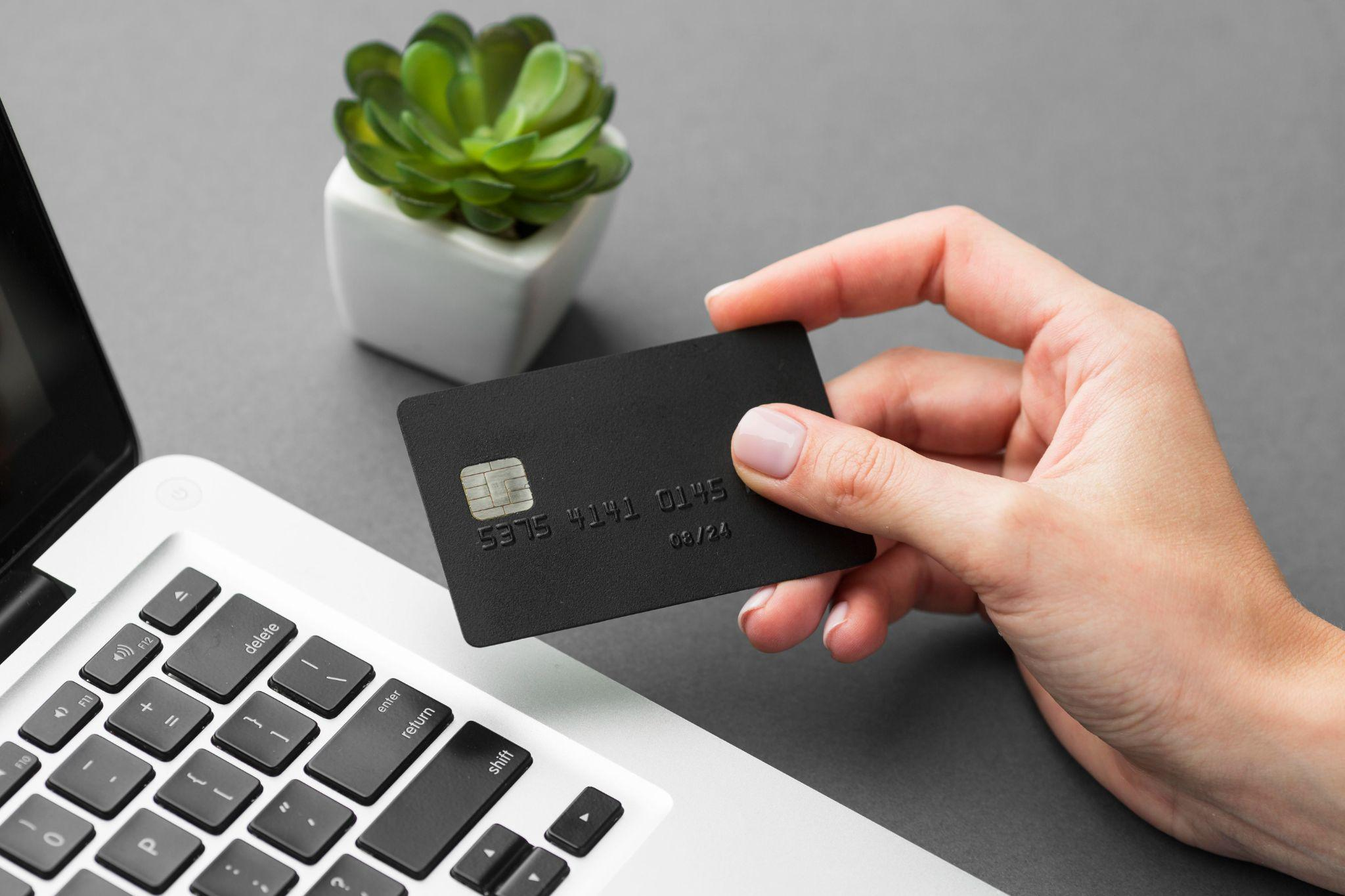 Microsoft Office 2021 Price Guide: What You Should Expect 2 close-up of a person's black credit card next to a MacBook as they make a purchase