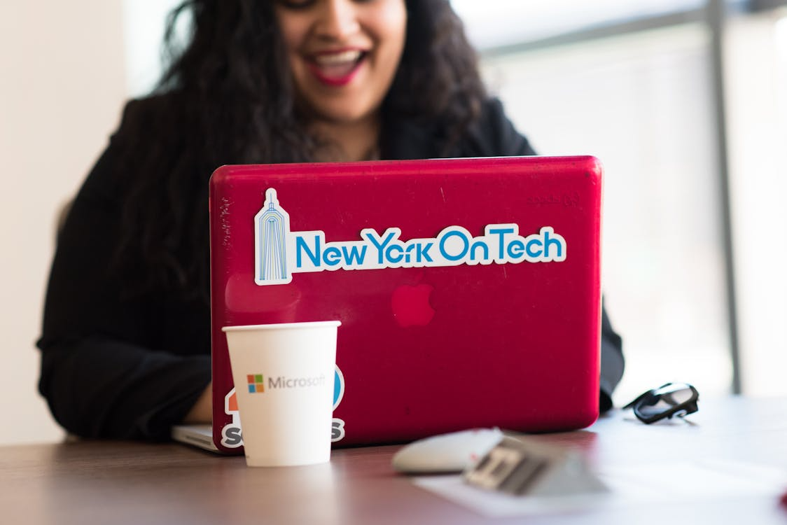 What You’re Really Paying for with Microsoft Office 2024 3 a woman using a red MacBook with a Microsoft logo cup placed in front of it